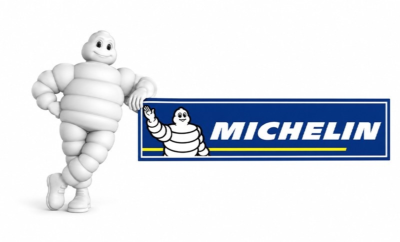 michelin man stands next mechelin logo